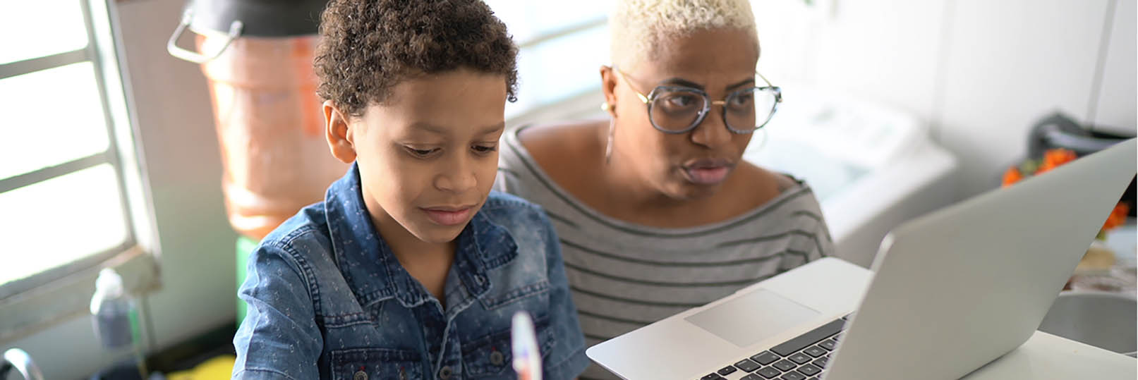 a mother and her young son working together on his remote learning